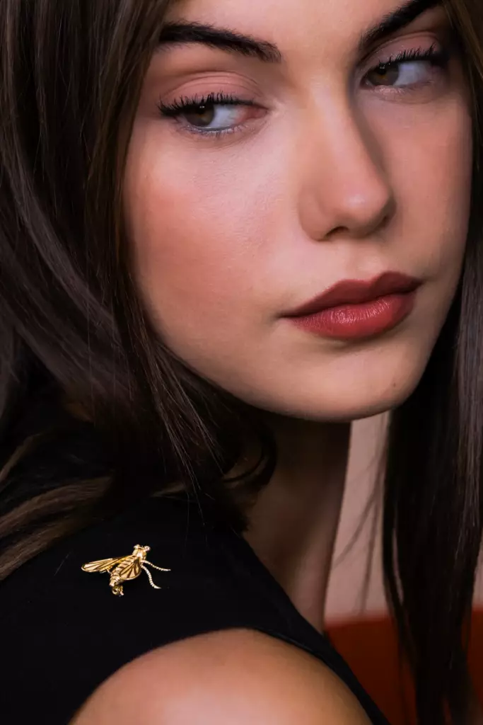 Portrait d'une femme de profil portant une broche dorée en forme d'insecte