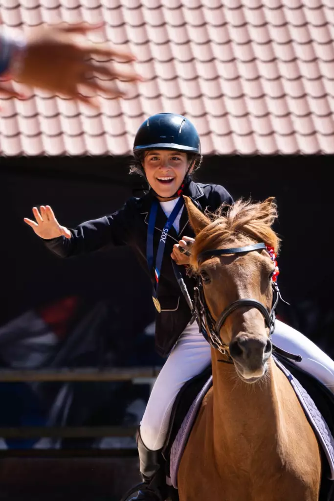 Enfant à cheval sur un poney, saluant lors d'un concours d'équitation