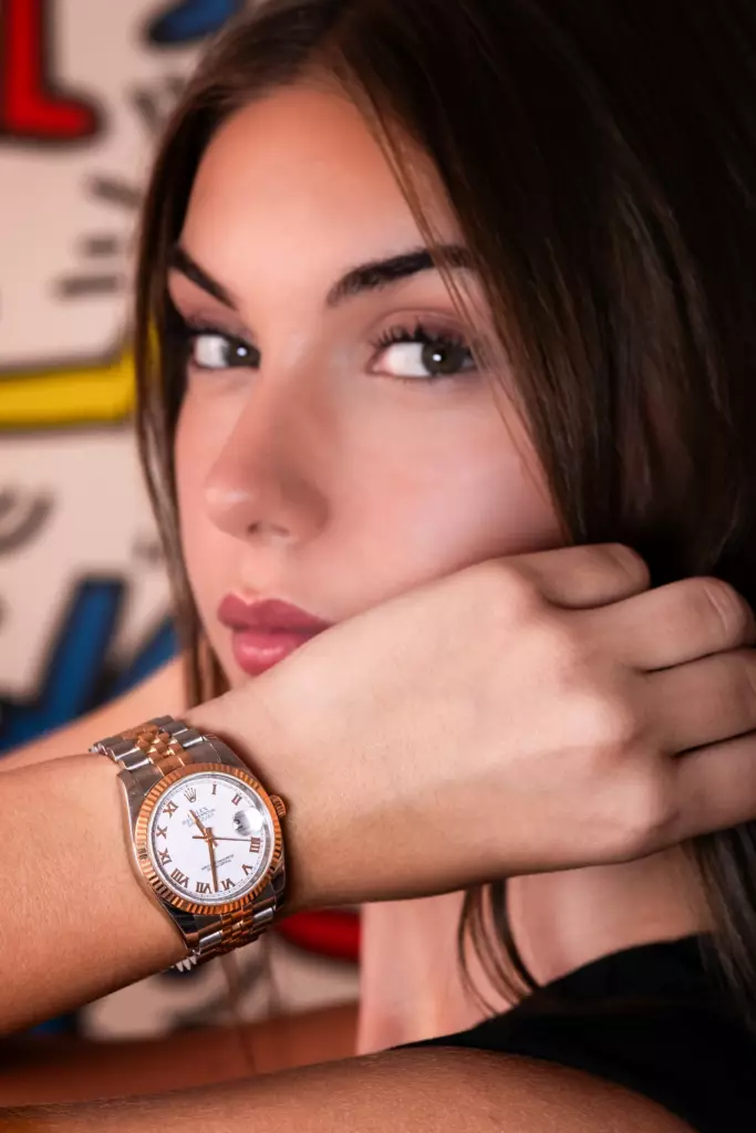 Femme posant avec une montre bicolore or rose et acier devant un fond coloré