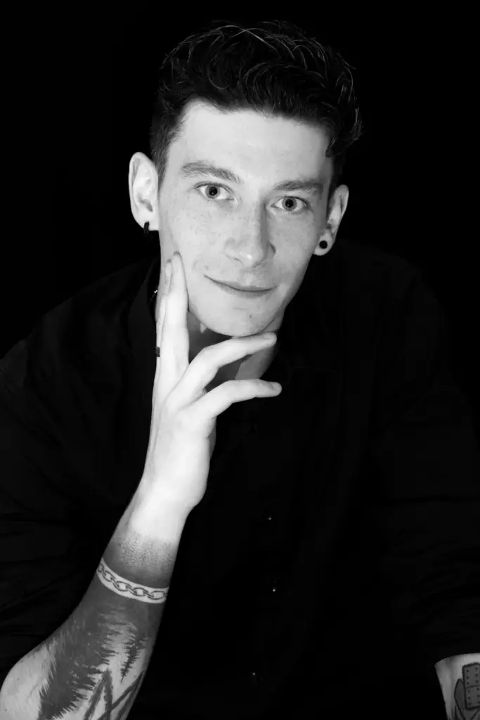 Portrait en noir et blanc d'un homme tatoué, la main sous le menton