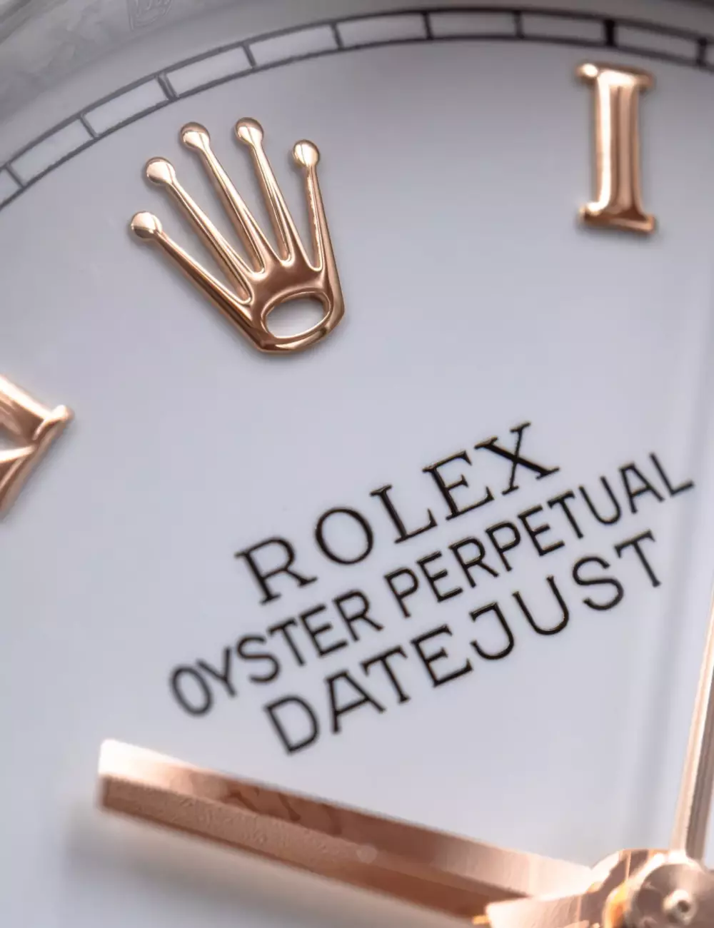 Macro du cadran d'une Rolex Datejust, couronne et index en or rose sur fond blanc laqué