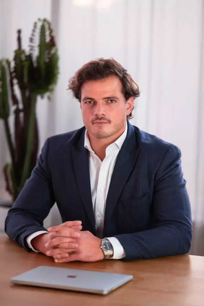 Portrait corporate d'un homme en costume bleu, mains jointes sur une table en bois